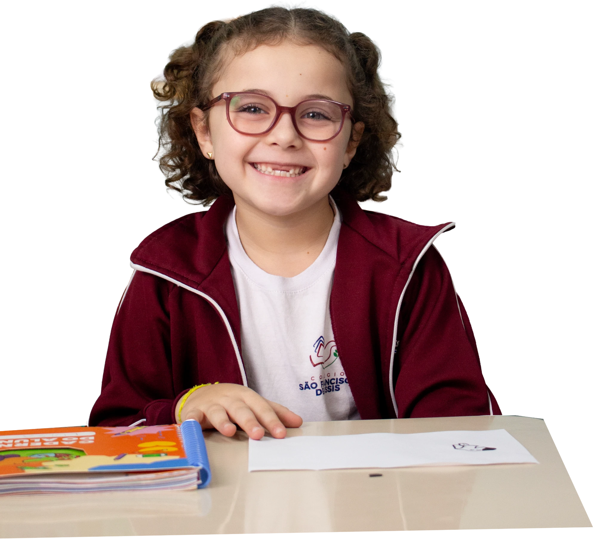 Aluna do SFA sorrindo, sentada à mesa com seu caderno